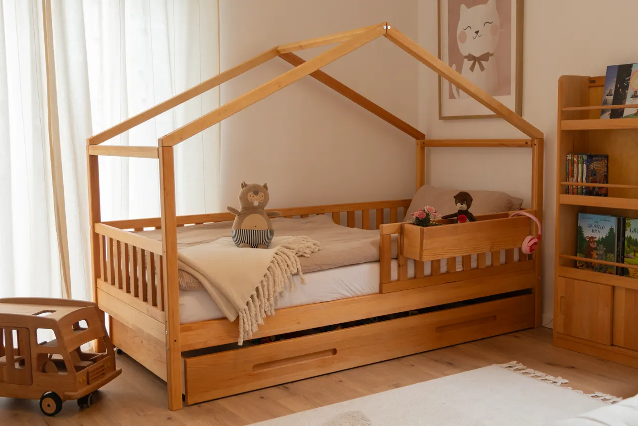 Hausbett aus Holz mit Kuscheltier in einem hellen Kinderzimmer
